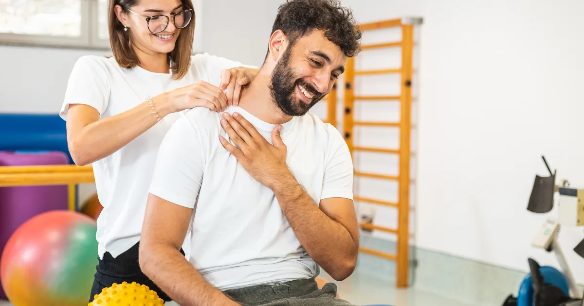 Physical therapist doing hands-on shoulder treatment with a smiling patient